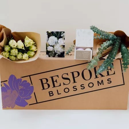 Bespoke Blossoms branded box, eucalyptus bunch, tulips, and bath bombs.